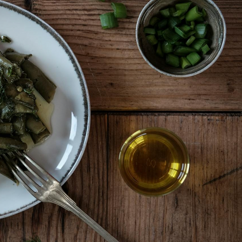 Olive oil drizzled over cooked greens on a wooden table