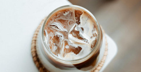 Iced pistachio cream latte in a glass on a wooden table