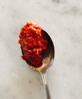 overhead view of a spoonful of Calabrian hot pepper cream on a marble surface