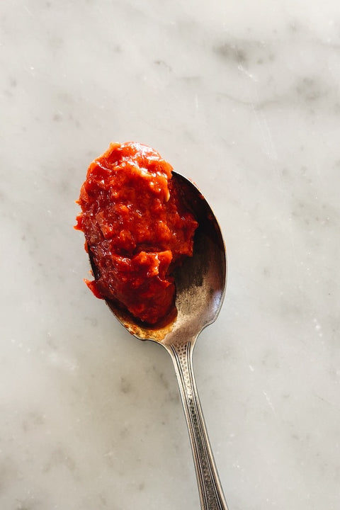 overhead view of a spoonful of Calabrian hot pepper cream on a marble surface