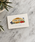 Tutto Sicilia Gift Card sitting on a marble counter top with olive branches in a bowl nearby.