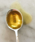Spoonful of extra virgin olive oil, close-up on marble