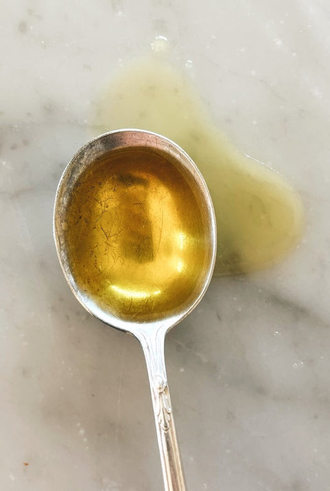 Spoonful of extra virgin olive oil, close-up on marble