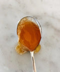 Spoonful of orange blossom honey, close-up on marble