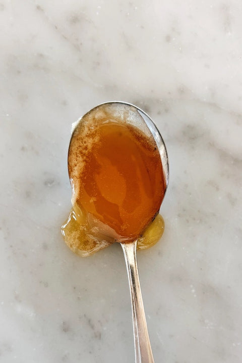 Spoonful of orange blossom honey, close-up on marble