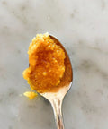 Spoonful of blood orange marmalade, close-up on marble