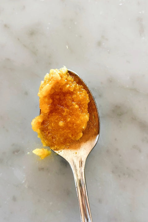 Spoonful of blood orange marmalade, close-up on marble