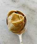 Overhead view of a vintage silver spoon holding a scoop of pistachio cream on a marble surface