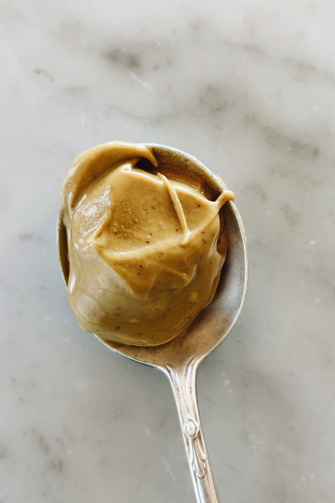 Overhead view of a vintage silver spoon holding a scoop of pistachio cream on a marble surface