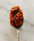 Spoonful of sun-dried tomato paté, close-up on marble